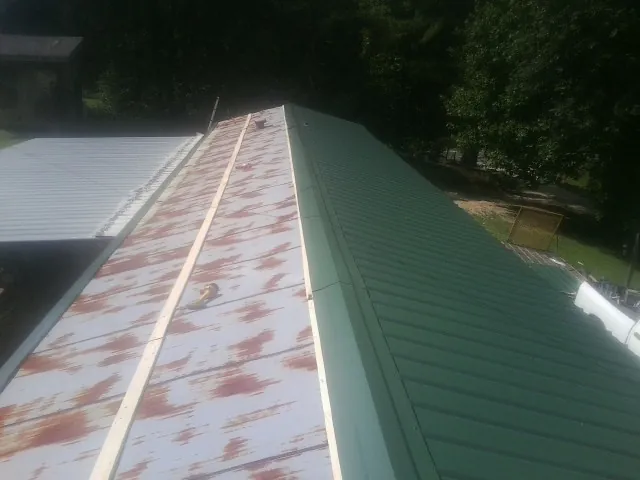 Old rusted panels beside newly installed green metal roofing — Wind Damage Roof Repair by Roofing Brothers in Groveland