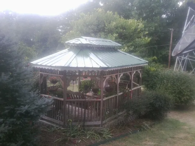 Green metal roof on a backyard gazebo surrounded by garden beds in Groveland
